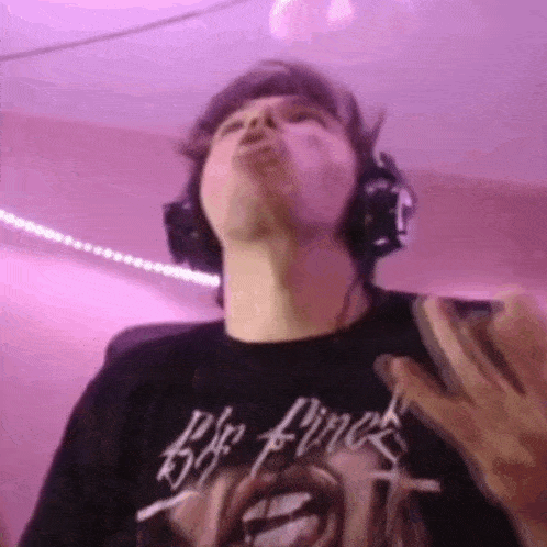 a man wearing headphones and a black shirt is blowing a kiss while looking up at the camera .