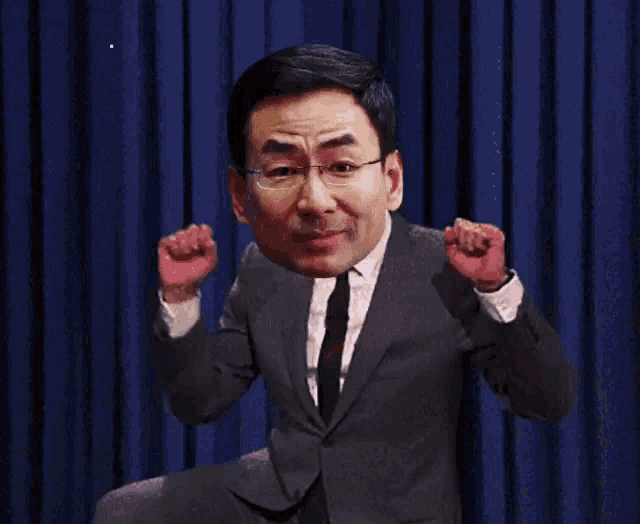 a man in a suit and tie is dancing in front of a blue curtain that says standnews on the bottom