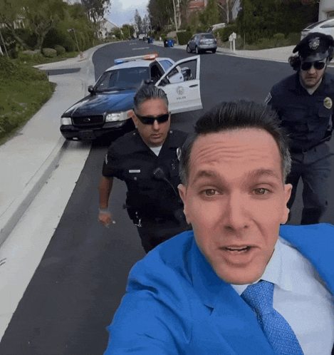 a man in a blue suit is taking a selfie with two police officers