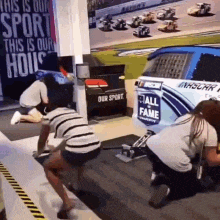 a group of people are working on a race car in front of a sign that says " this is our sport this is our house "