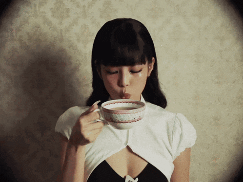 a woman drinking from a cup with a floral design