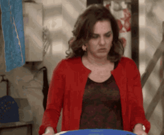 a woman in a red cardigan holds a blue bucket