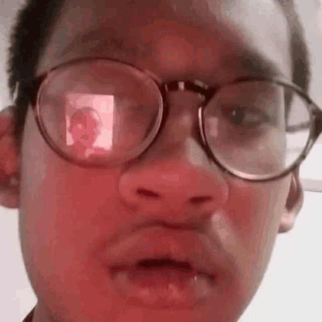 a close up of a person wearing glasses with a reflection of a person in the lenses .