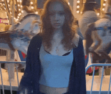 a woman is standing in front of a merry go round with a sign that says fun