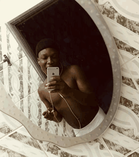 a shirtless man is taking a picture of himself in the mirror
