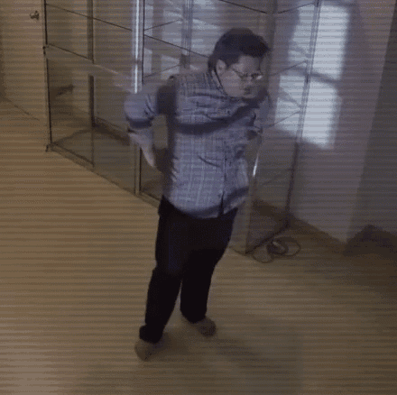 a man in a plaid shirt and black pants is dancing in front of a glass display case .