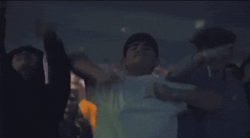 a man in a white shirt is dancing in a dark room