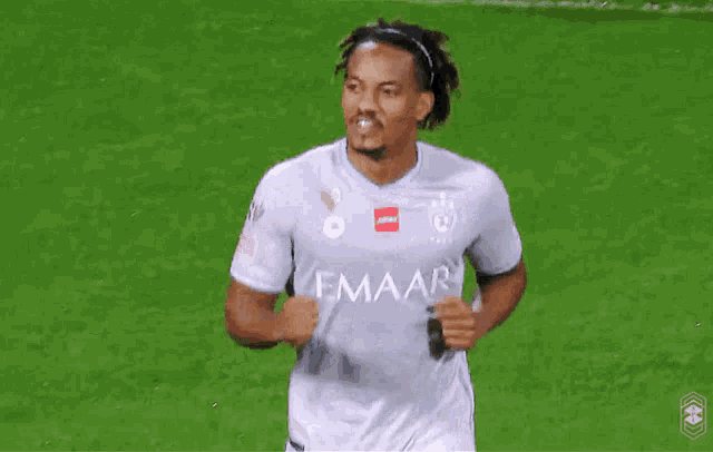 a soccer player wearing a gray emaar jersey is running on the field
