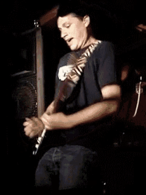 a man is playing a guitar in a dark room