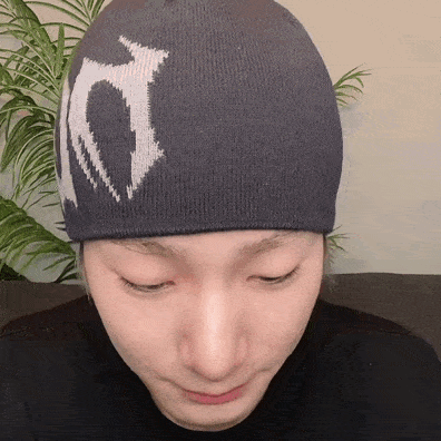 a close up of a person wearing a beanie with a white letter t on it