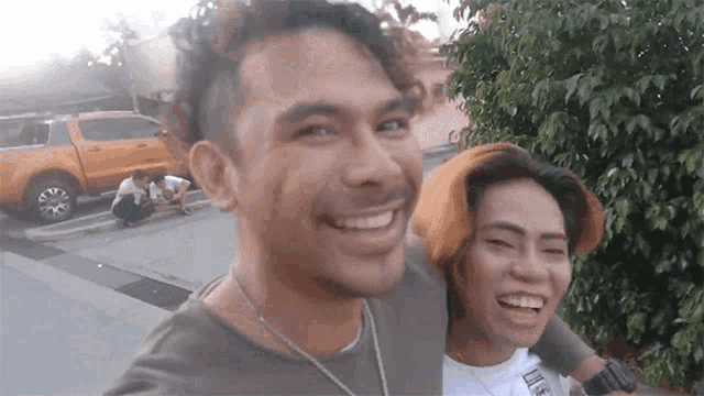 a man and a woman are smiling and laughing while standing next to each other on a street .