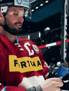 a hockey player wearing a red jersey with a yellow stripe that says fortuna