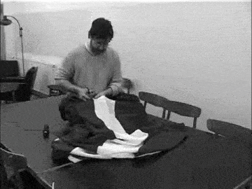 a man is cutting a piece of fabric on a table .