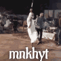 a woman in a white dress is holding a bat in her hand while dancing .