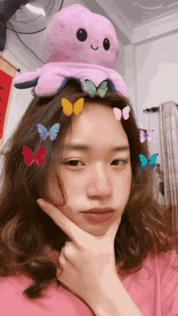 a girl has a stuffed octopus on her head with butterflies in her hair