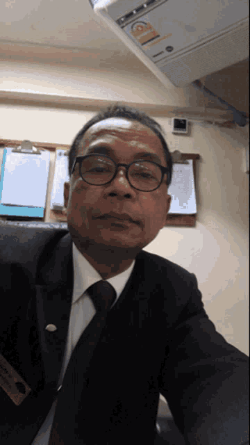 a man in a suit and tie takes a selfie in front of an air conditioner