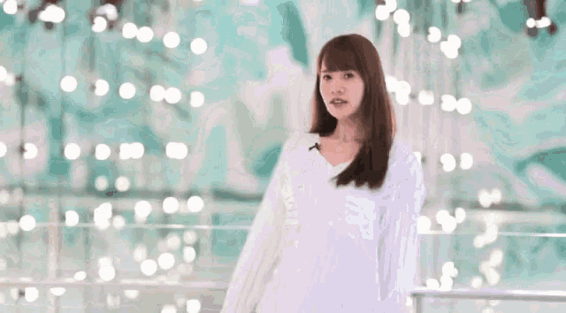 a woman in a white shirt is standing in front of a blurred background .