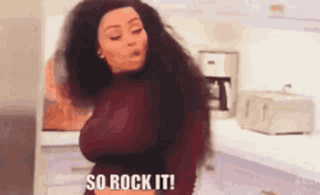 a woman is standing in a kitchen with her hair blowing in the wind and the words so rock it .