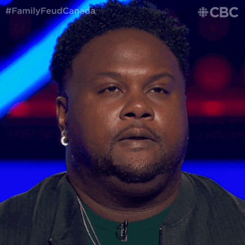 a man with curly hair and a beard looks at the camera with a cbc logo in the corner