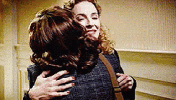 two women are hugging each other in a room in a room .