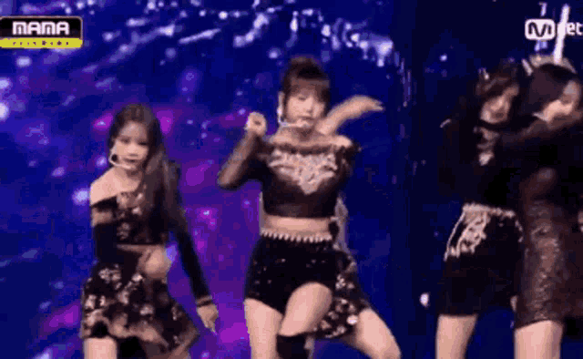 a group of women are dancing on a stage with a mnet logo in the background .