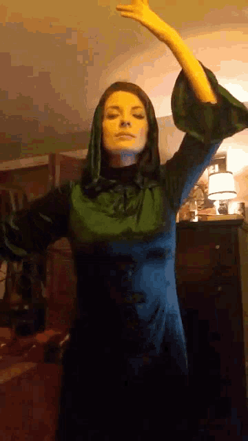 a woman in a green dress is dancing in a room