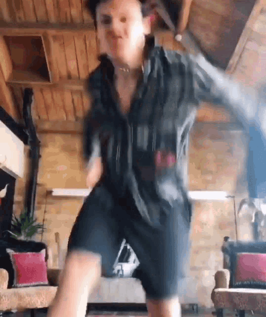 a man is dancing in a living room with a wooden ceiling .