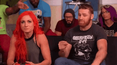 a man and a woman are sitting next to each other in a crowd . the woman is wearing a shirt that says operation