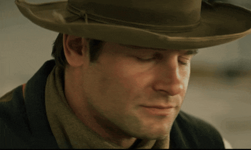 a close up of a man wearing a cowboy hat with his eyes closed