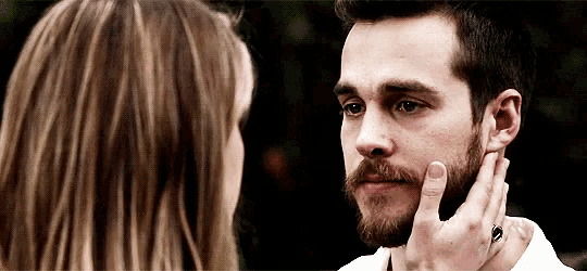 a woman is touching a man 's beard with her hand .