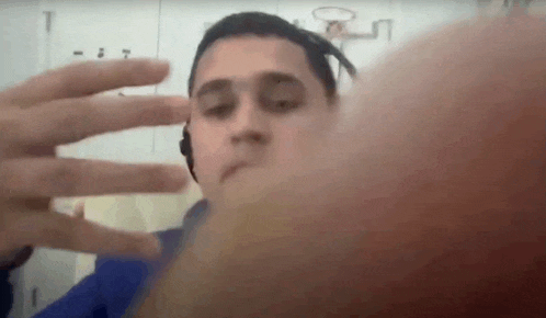 a young man wearing headphones is taking a selfie with his hands .