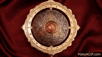 a circular object with a red stone in the center is on a red cloth and says makeagif.com