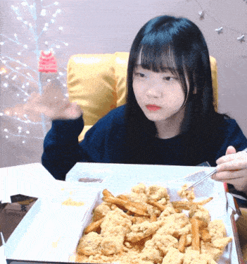 a girl eating fried chicken and french fries with chopsticks