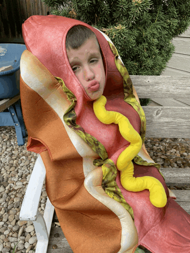 a young boy in a hot dog costume with mustard on it
