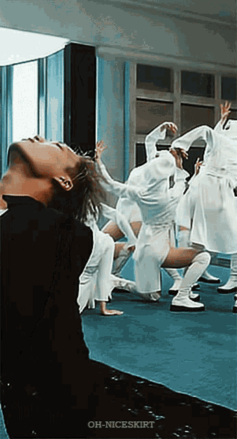 a man in a black shirt stands in front of a group of dancers with oh-niceskirt written on the bottom right