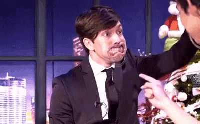 a man in a suit and tie is making a funny face while another man points at him