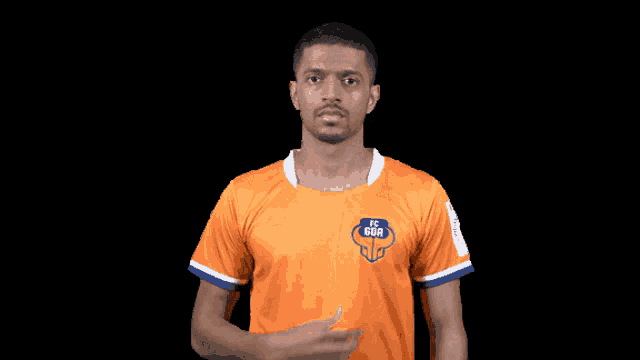 a man in an orange fc goa jersey holds his fist up