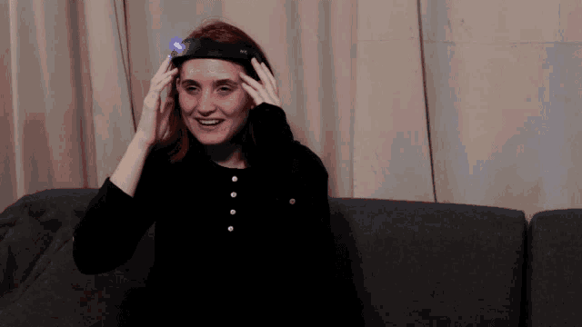 a woman sitting on a couch wearing a headband with a light on it