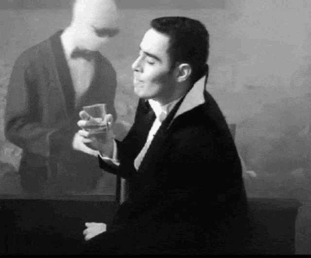 a man in a tuxedo is holding a glass of alcohol