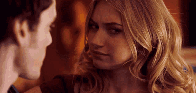 a man and a woman are looking at each other and the woman has a serious look on her face