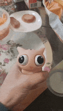 a person is holding a toy in their hand with big eyes
