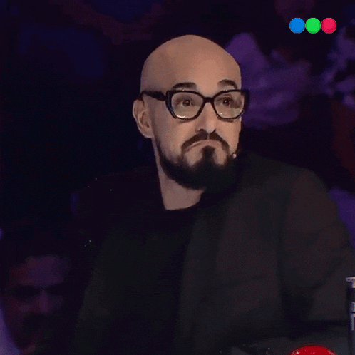 a man with glasses and a beard is giving a thumbs up