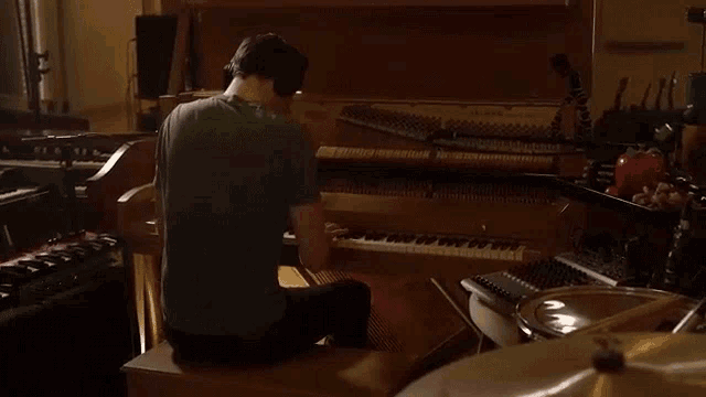 a man in a green shirt is playing a piano in a room