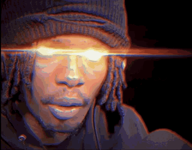 a man with dreadlocks wearing a beanie has a bright light coming from his eyes .