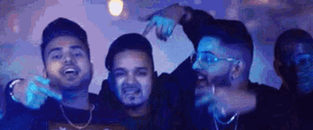 a group of young men are standing next to each other in a dark room in front of a blue light .