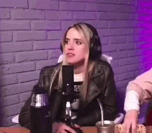 a woman wearing headphones is sitting at a table with a microphone .