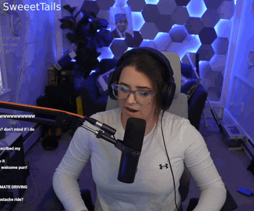 a woman wearing headphones and a white under armour shirt stands in front of a microphone with the words sweettails above her