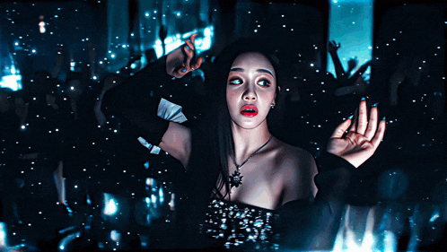 a woman in a black dress is standing in a dark room with her hands outstretched