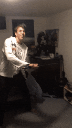 a man wearing a white sweatshirt with the letter m on it is standing in a dark room