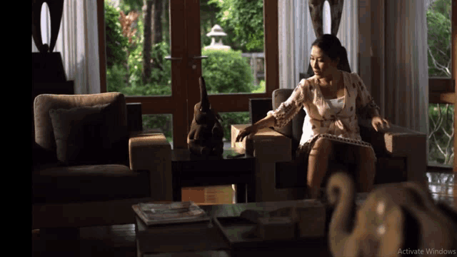 a woman sits in a chair in front of a window with activate windows written on the bottom of the screen